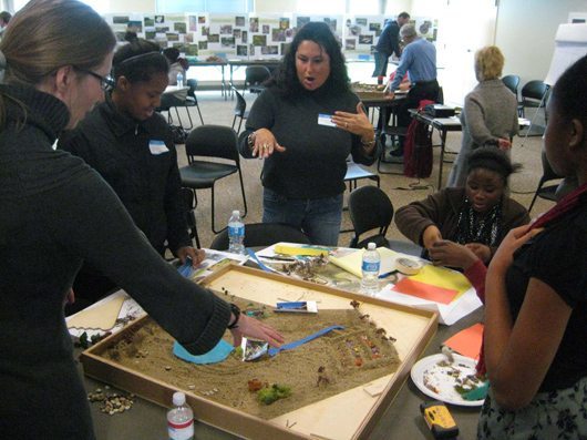 Community members working with sand models at the WeDesign workshop